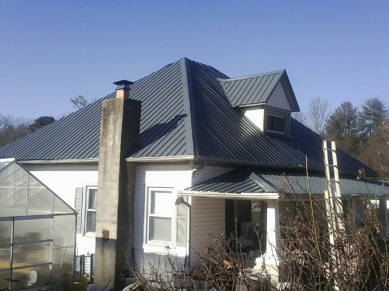 Dark blue standing seam metal roof on a white farmhouse with dormer — Slate & Tile Roof Repair by Roofing Brothers in Ronks