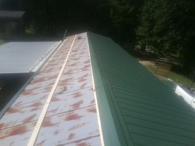 Old rusted panels beside newly installed green metal roofing — Wind Damage Roof Repair by Roofing Brothers in Ronks