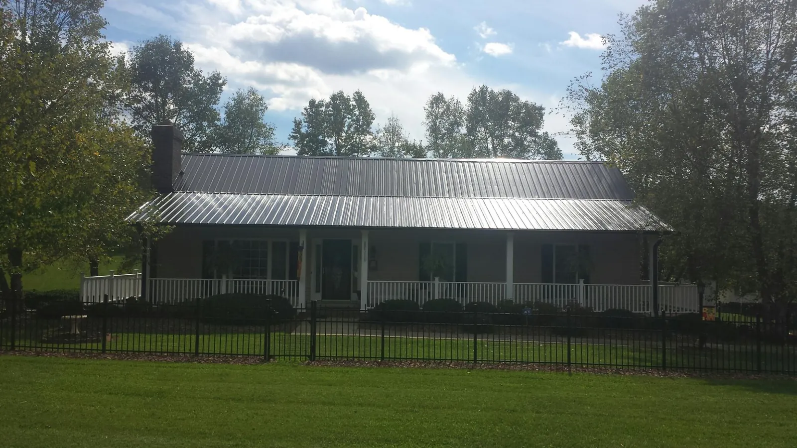Gray metal roof on a brick ranch with a full width front porch — Gutter Guard Installation work by our crew in Ronks