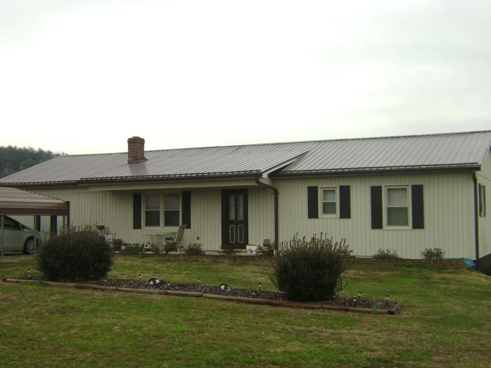 Brown metal roof on a cream sided ranch home with a brick chimney in Ronks