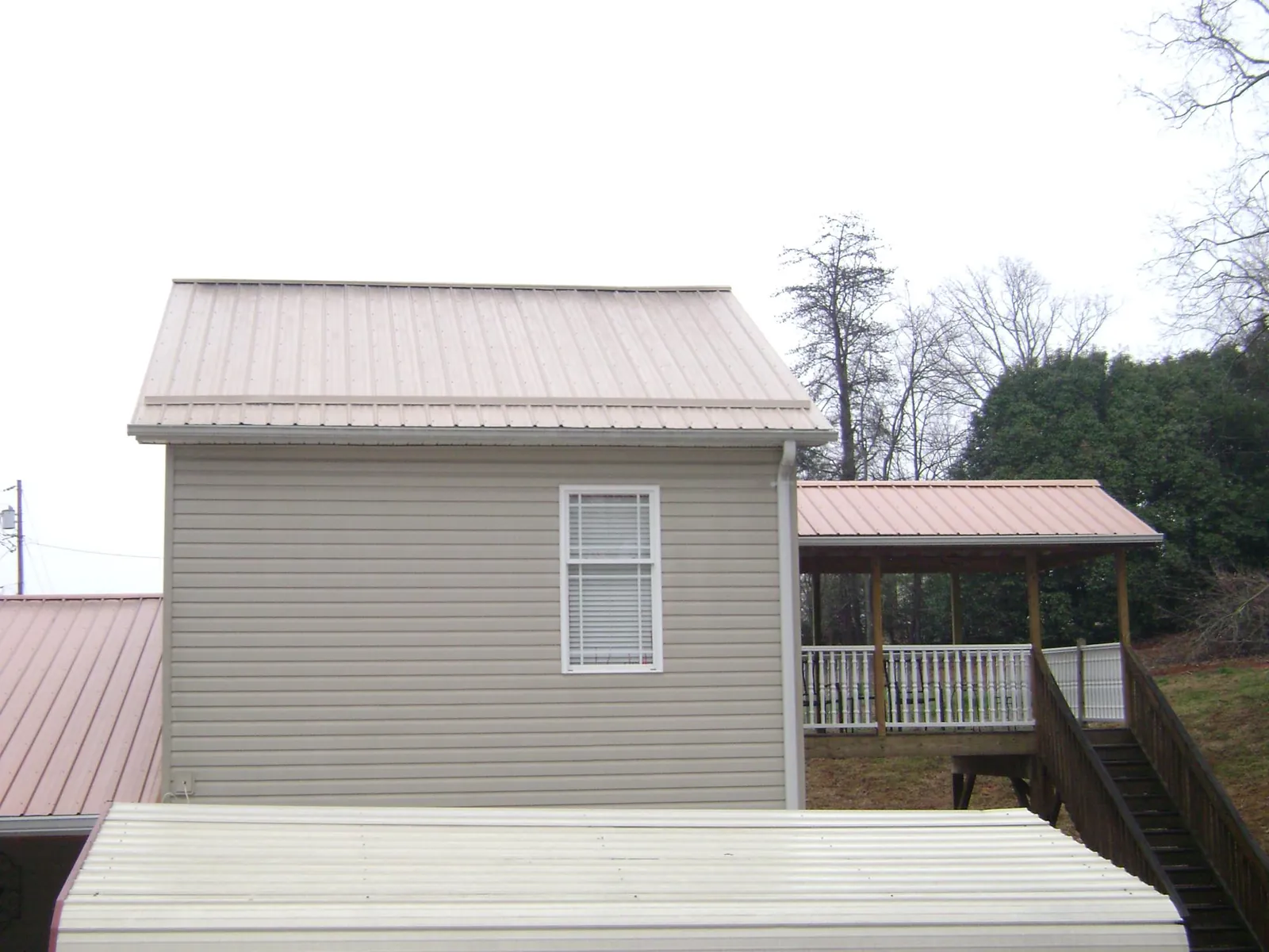 Tan metal roofs on a two story addition and attached porch, from a Roof Replacement job in Ronks