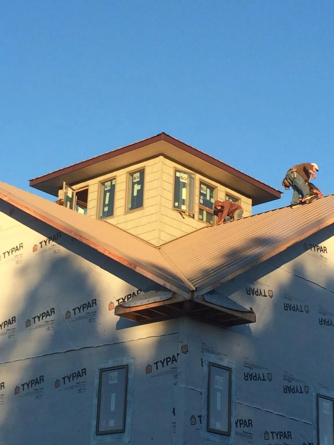 Roofers working around a rooftop cupola on a new metal roof at sunset — Roof Waterproofing in Ronks by Roofing Brothers